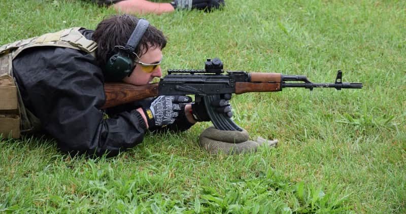 A shooter from Michigan AKM Owners taking aim with his WASR rifle. He's customized his gun with an aftermarket flash hider and optic mount.